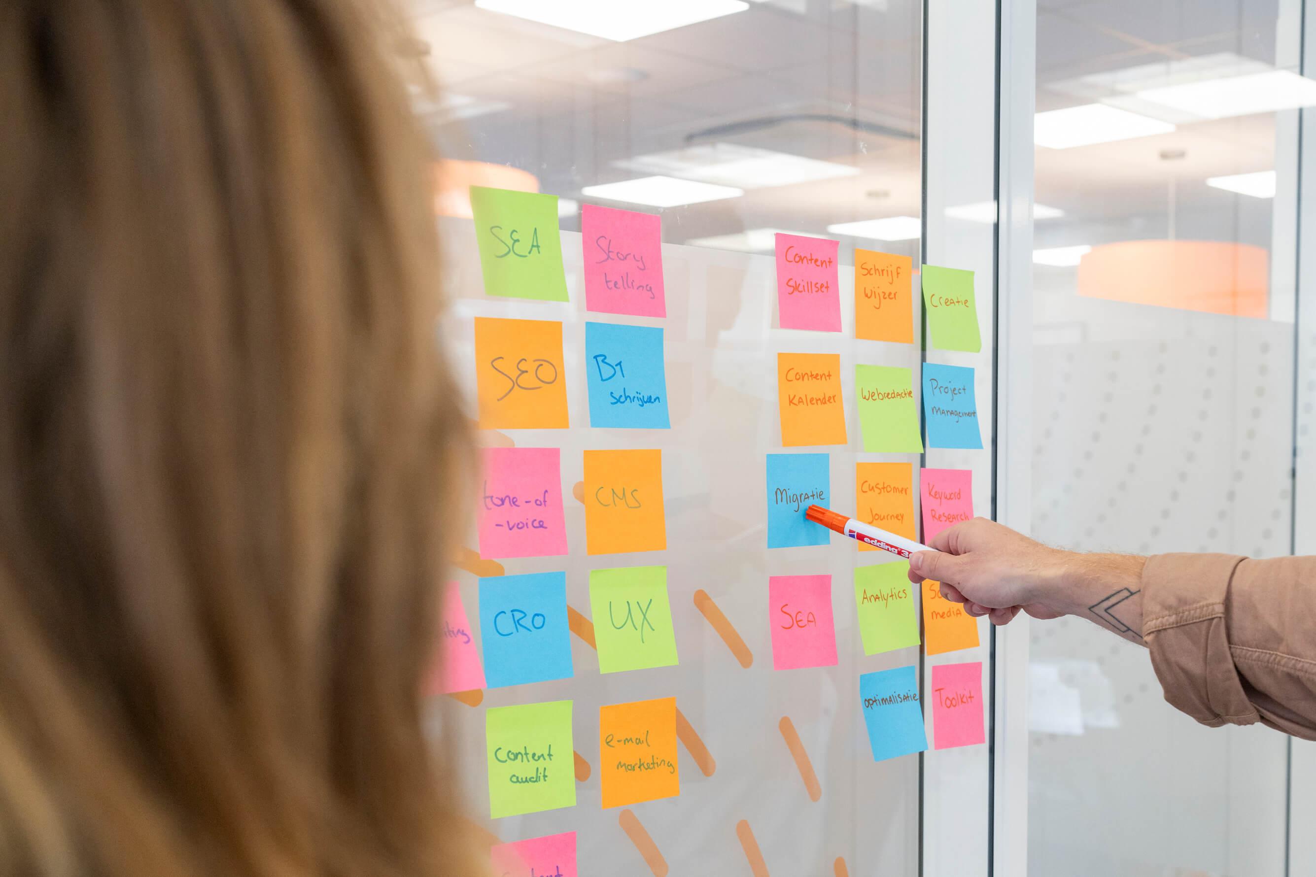 Persoon wijst met een pen op post-it