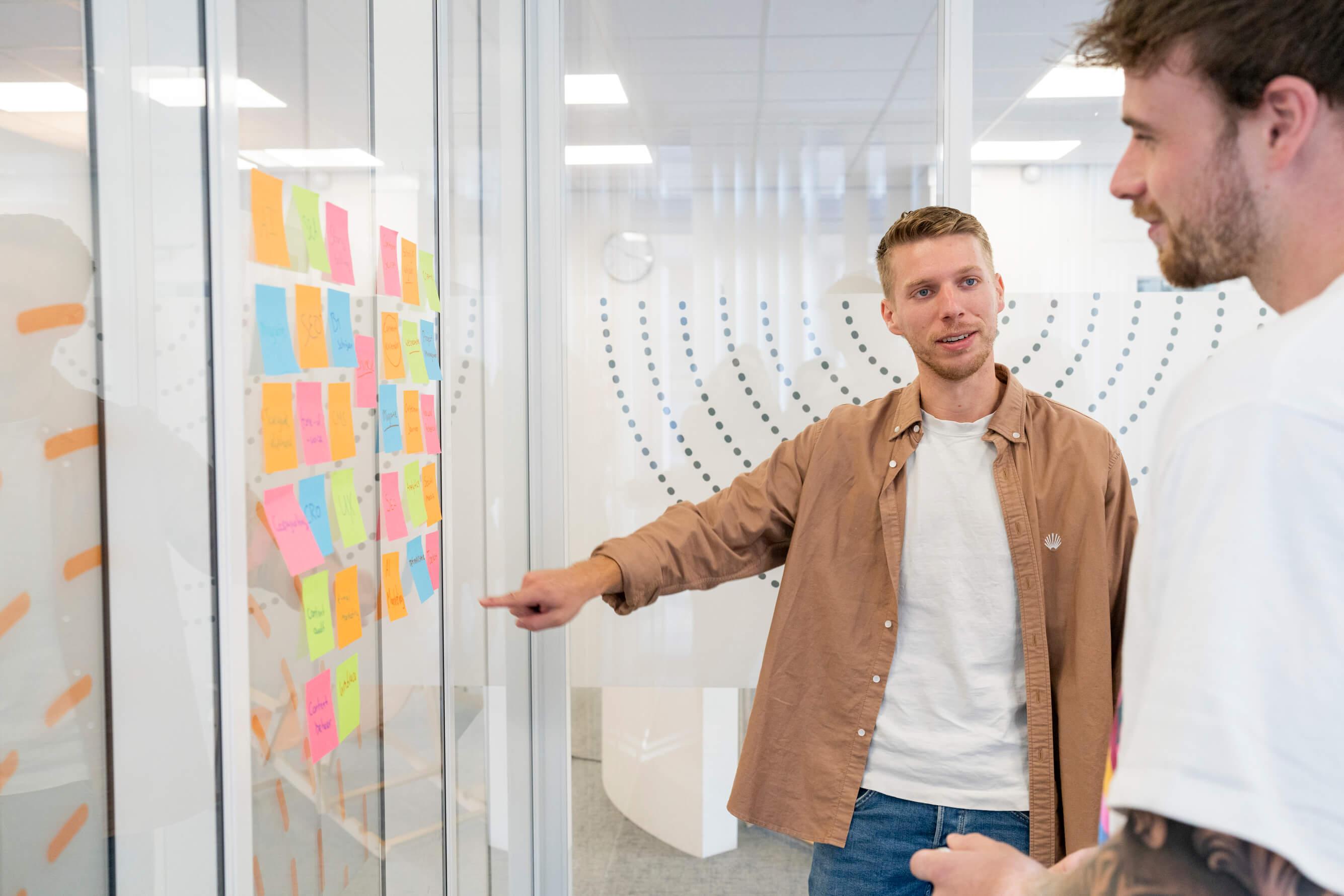 Collega's bespreken voor een muur met post-its