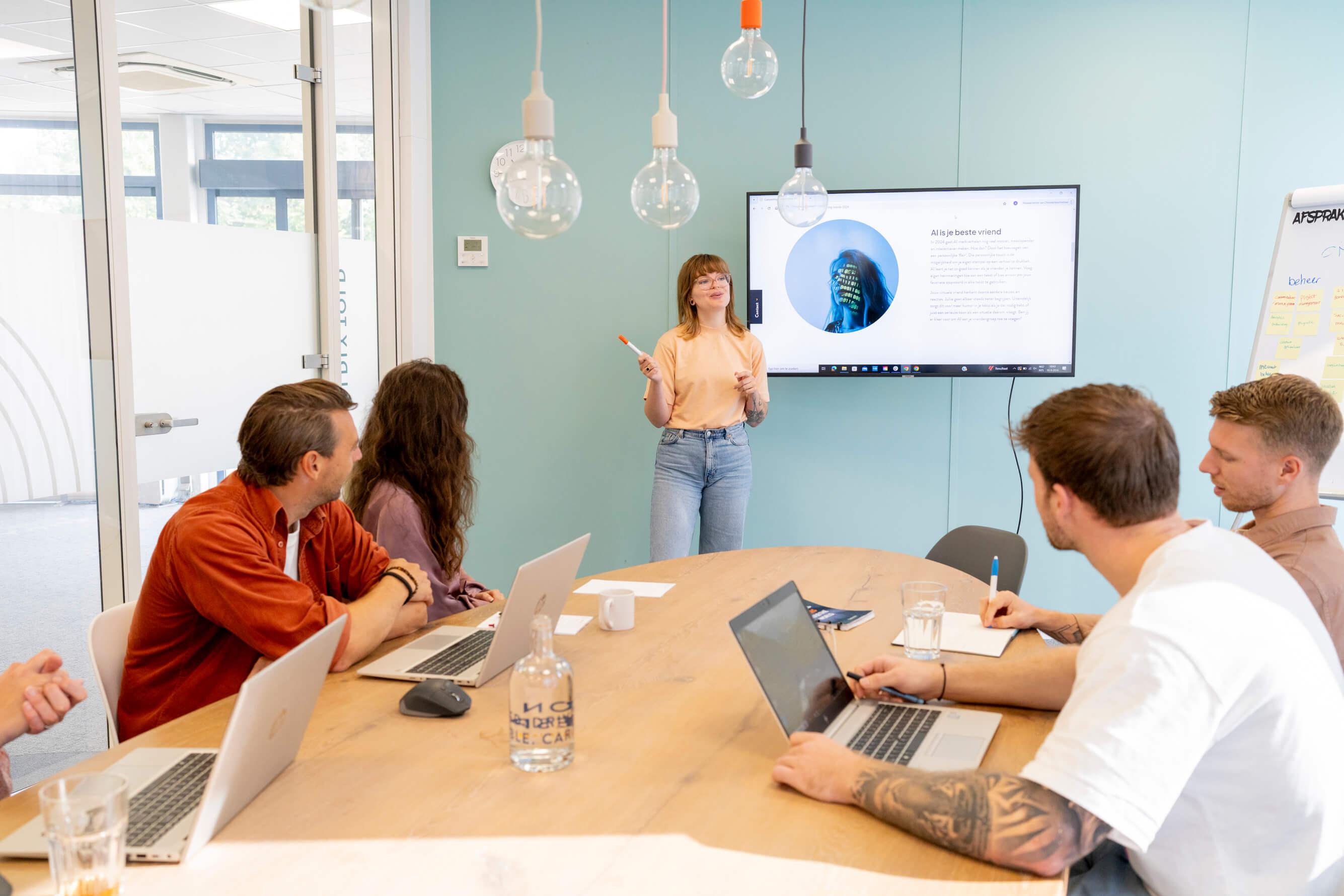 Vrouw geeft een presentatie aan een groep collega's in een vergaderruimte