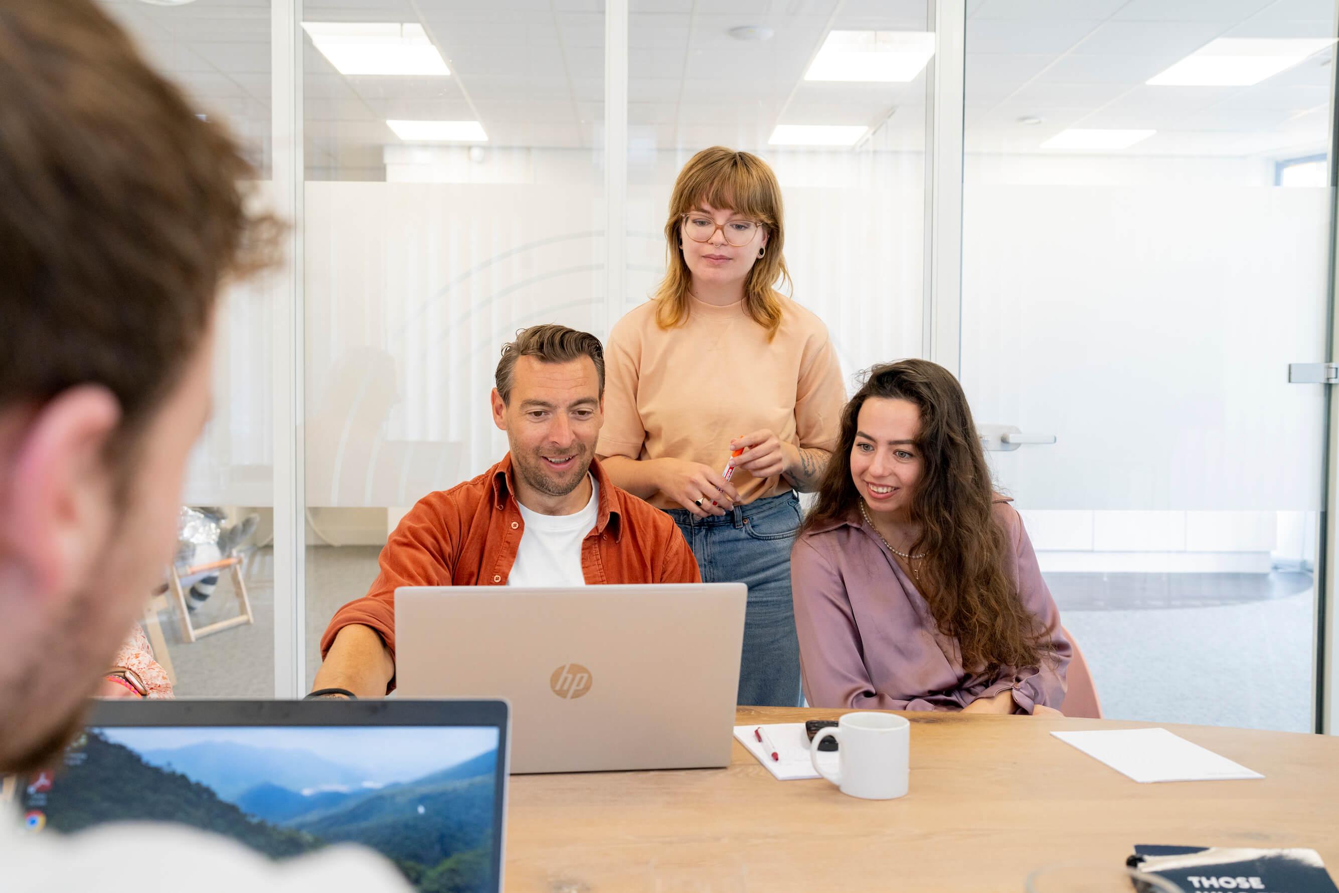 Collega's samen rond een laptop in een vergaderruimte