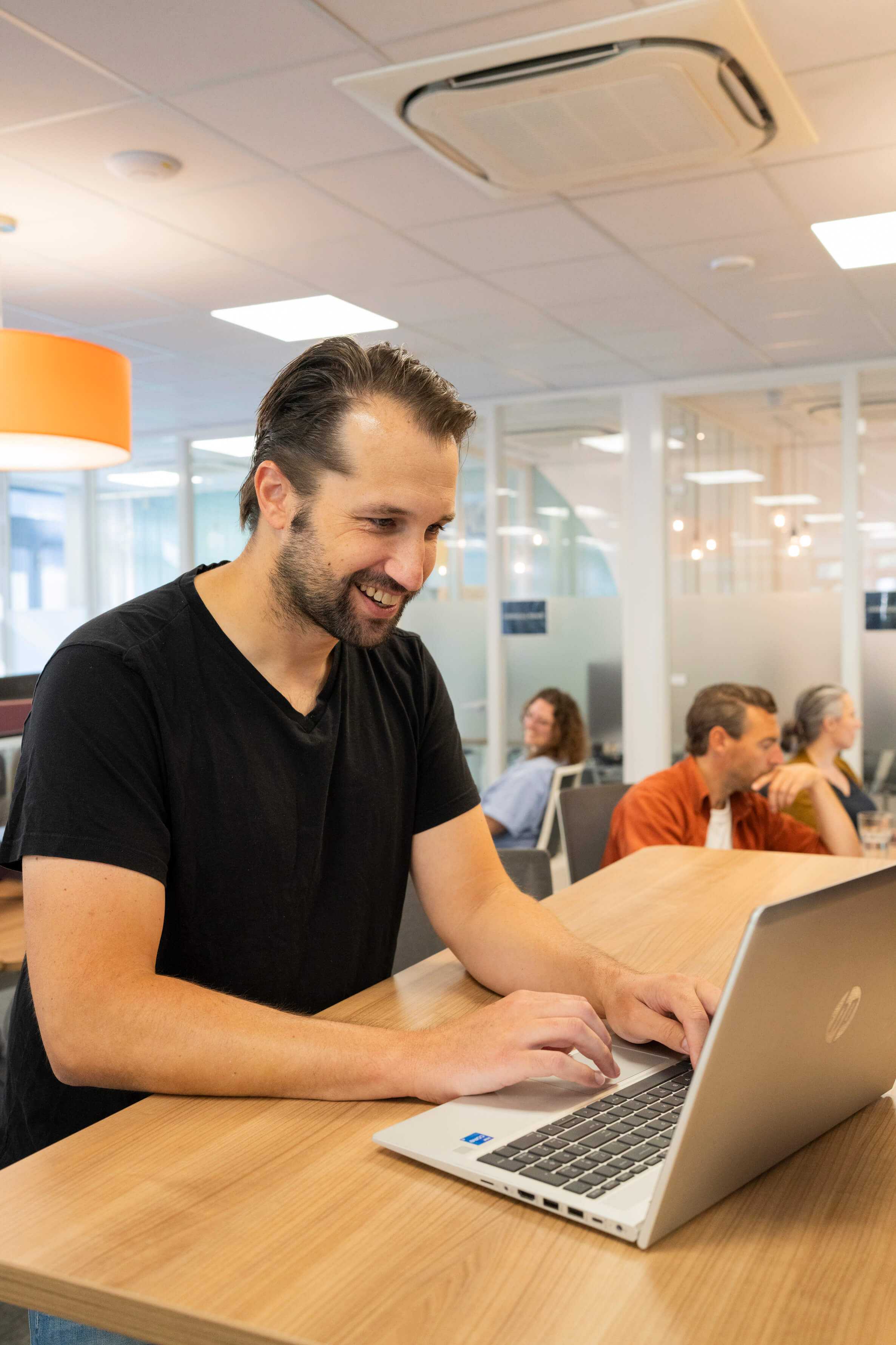 Man werkt lachend achter laptop