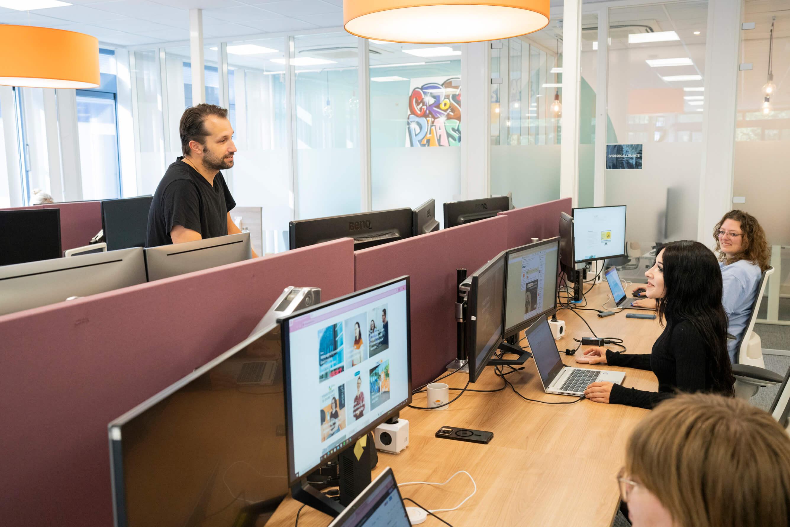 Collega's overleggen aan bureau in een open kantoorruimte