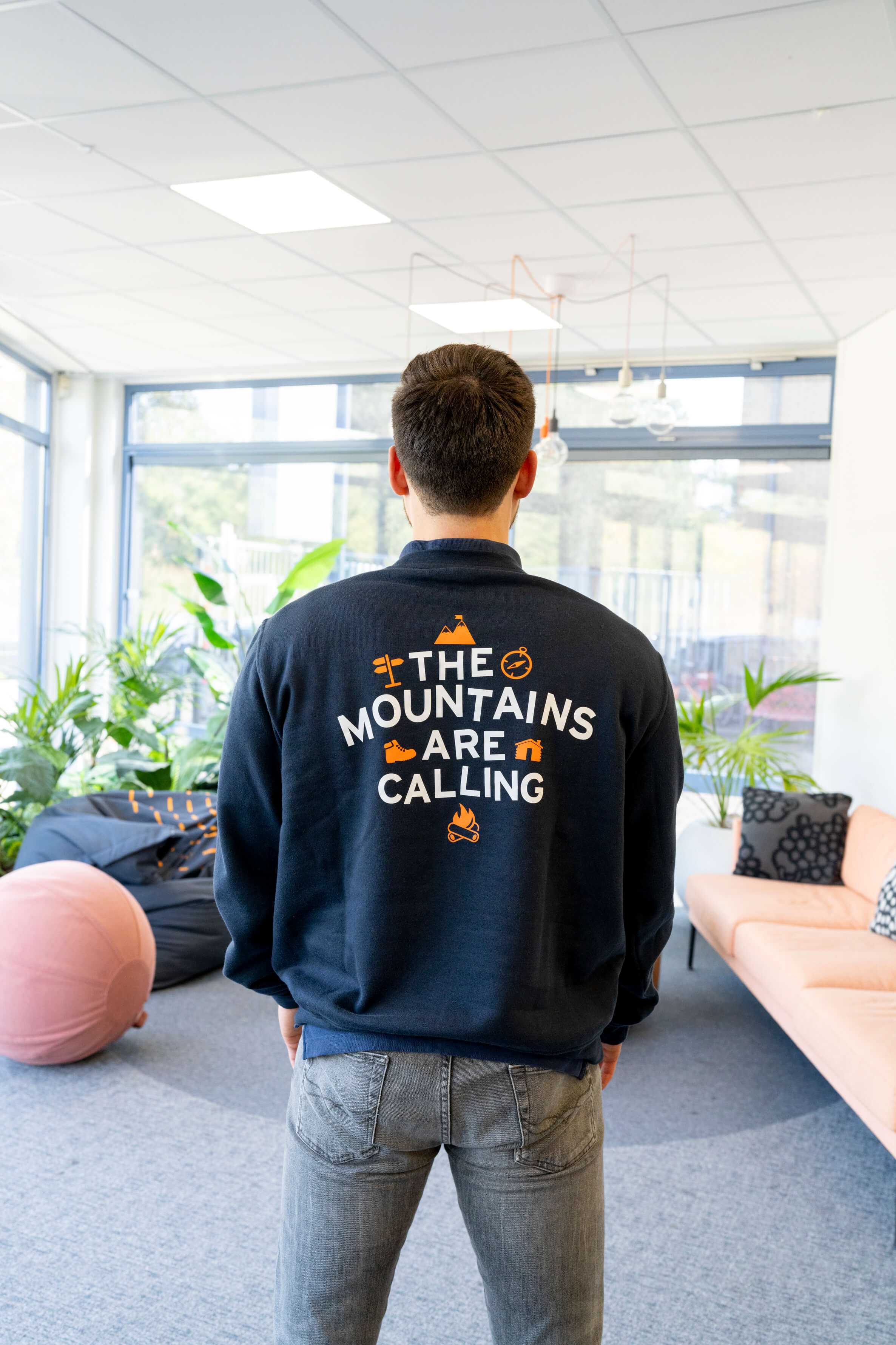 Man met een trui waarop 'the mountains are calling' staat