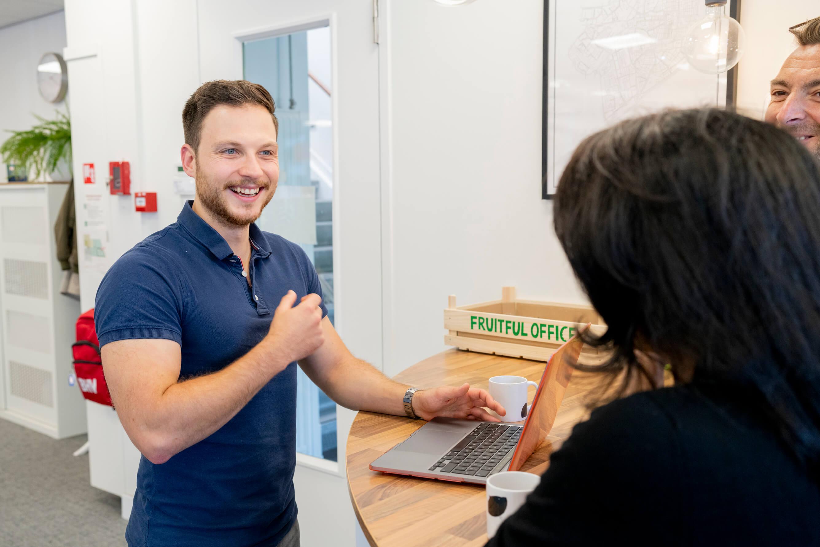 Man lacht tijdens een gesprek met twee collega's bij een koffietafel
