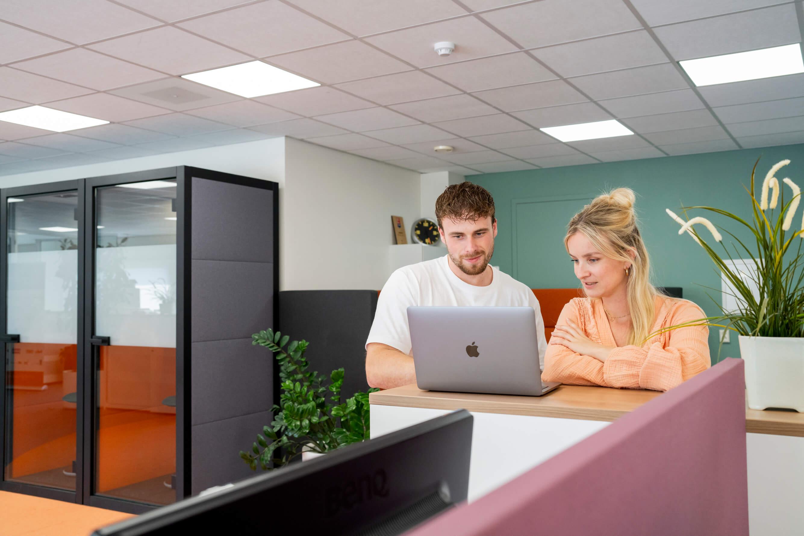 Twee collega's werken samen achter een laptop