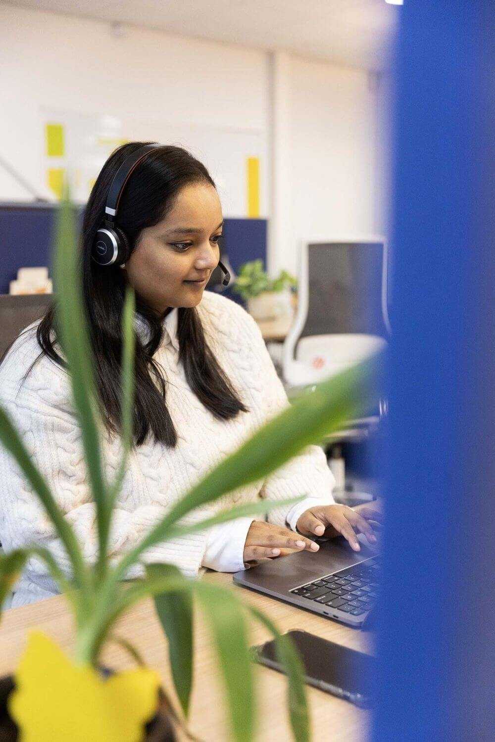 Vrouw werkt aan haar laptop met een headset op